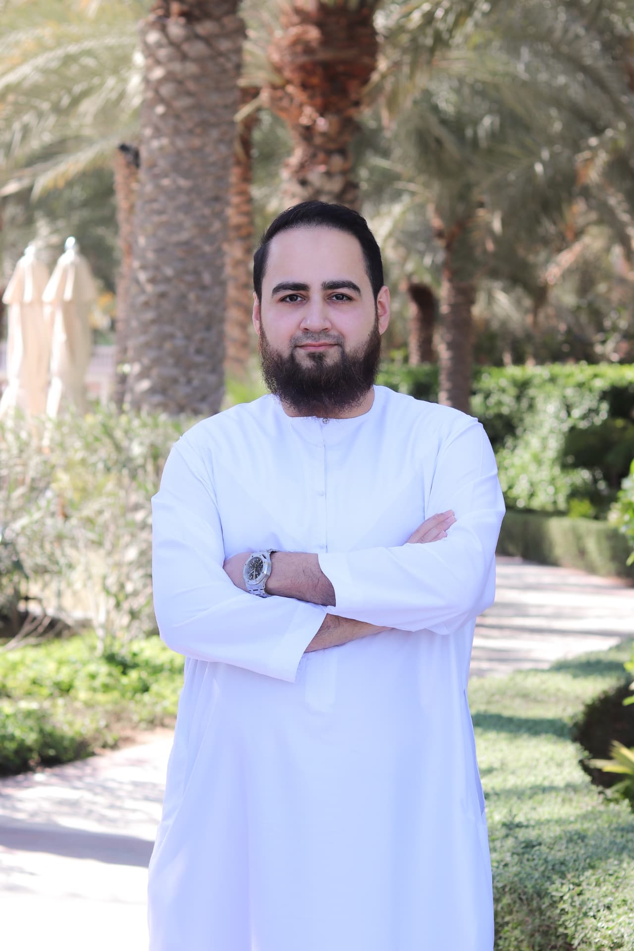 Huzefa Vorajee outdoors in Dubai, wearing a white kandura, arms folded